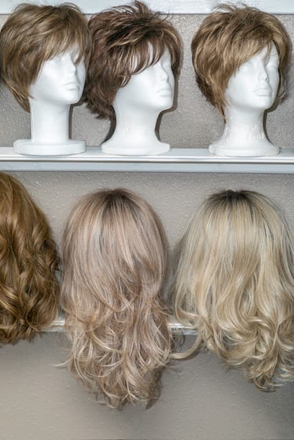 Two shelves of wigs on display heads in the studio.